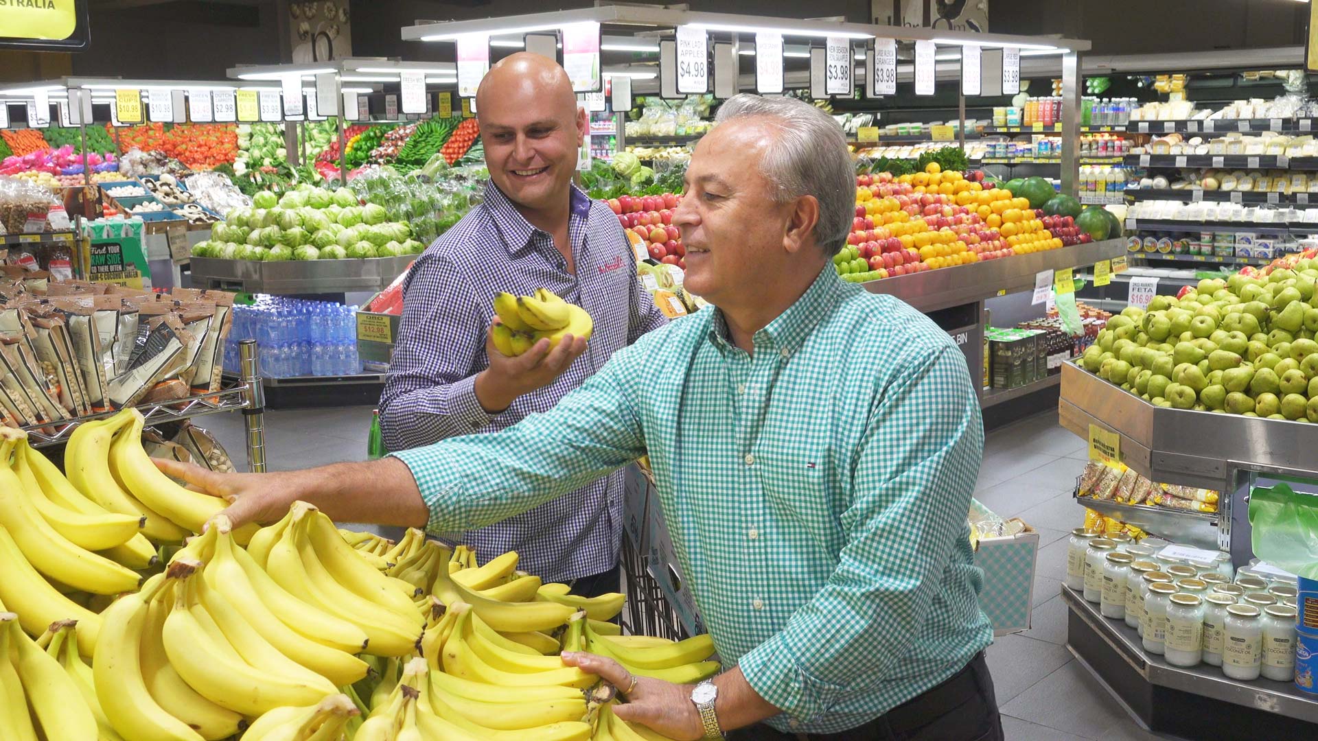 Two men in a market holding bananas