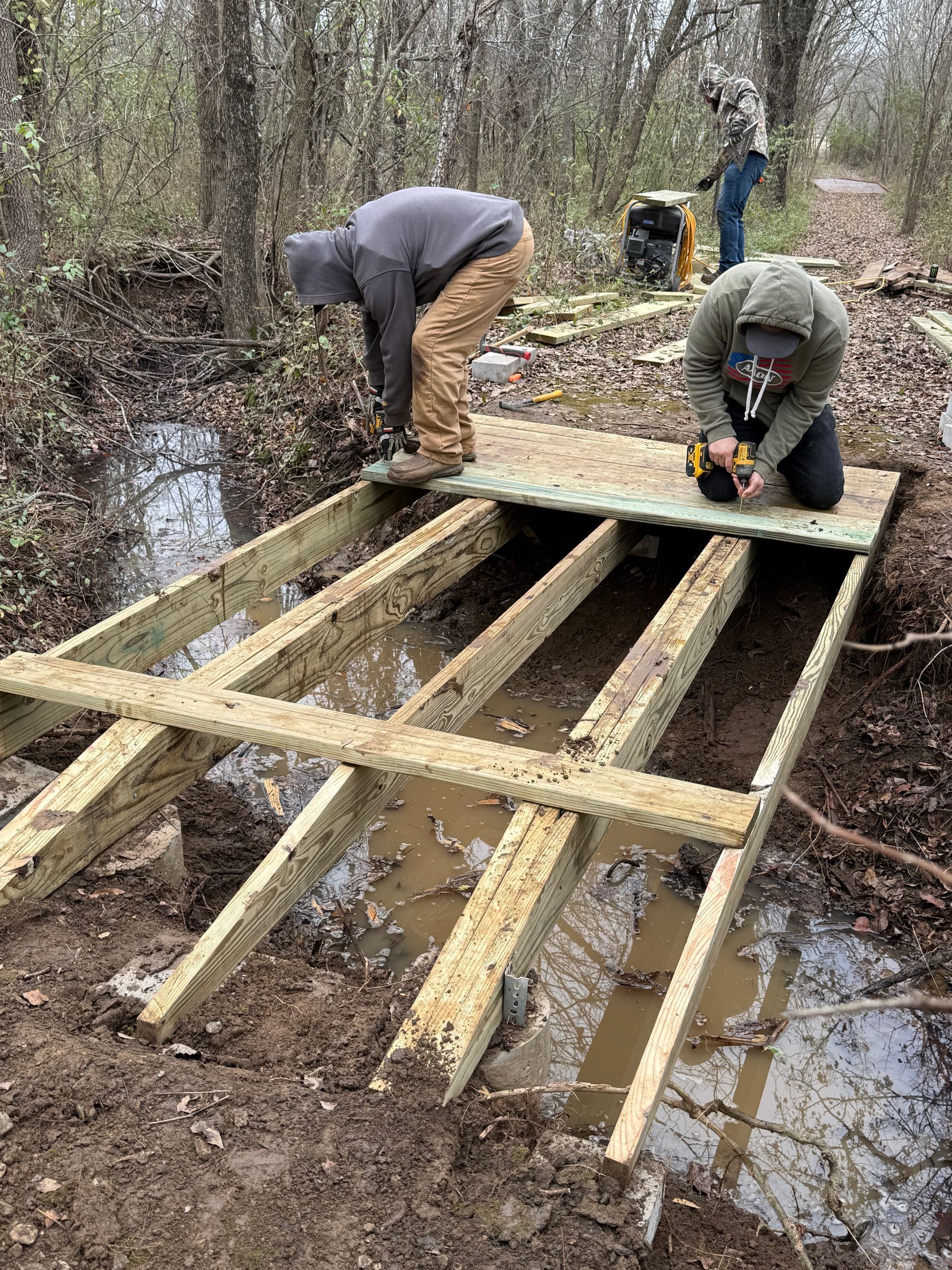 A small wooden building and a yellow shade canopy sit on a grassy field under a cloudy sky.