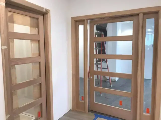 Wooden door with five glass panels, open to reveal a room with a ladder and construction materials.