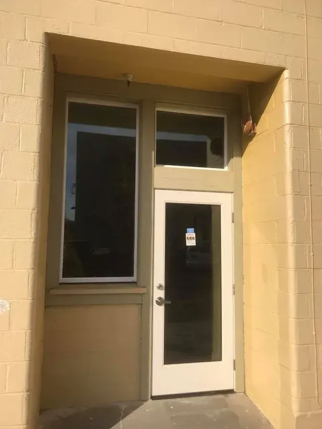 Exterior door with large side windows set into a recessed, tan brick facade.