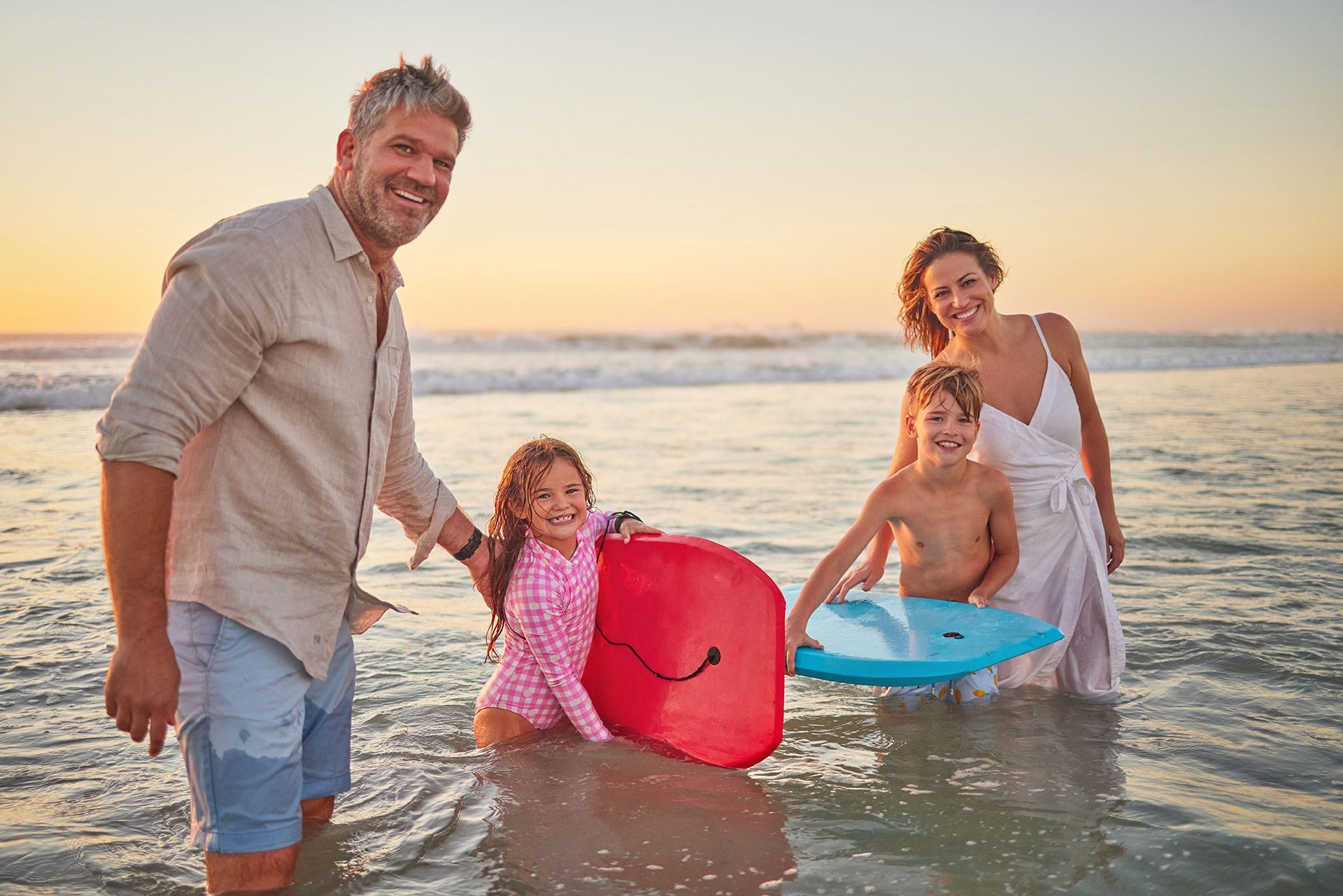 a family is standing in the water holding surfboards