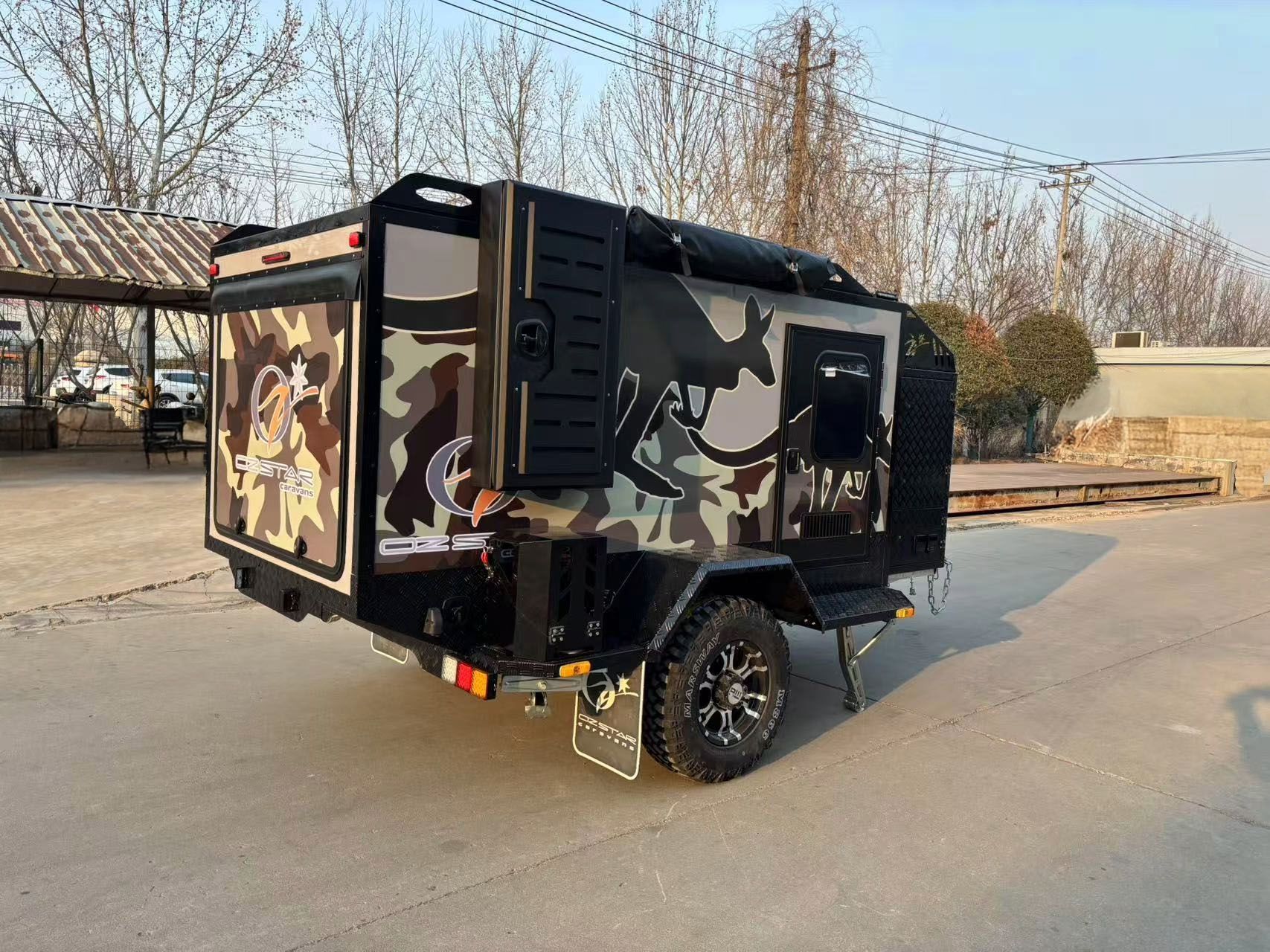 A small 7ft caravan trailer is parked on the side of the road.