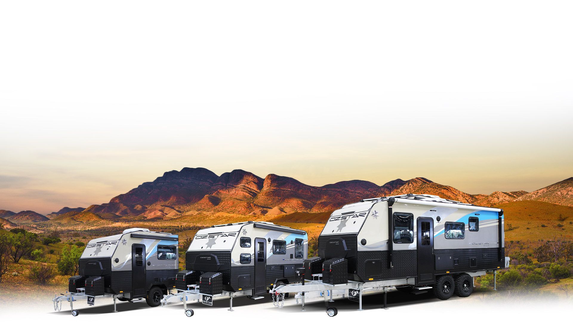 Three RVs are parked next to each other in the desert with mountains in the background.