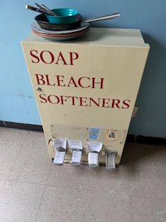 A soap bleach and softener dispenser with plates and bowls on top of it.
