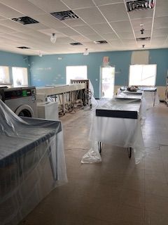 A laundromat with a washer and dryer and a table covered in plastic.