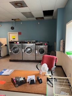 A laundromat with three washing machines and a desk.