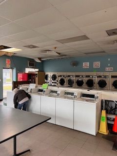 A laundromat with a lot of washers and dryers and a table.