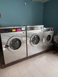 There are three washing machines in a laundromat.