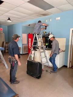 A group of men are working on a coca cola machine in a room.