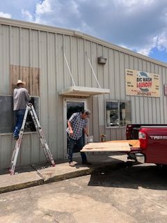 Two men are standing on a ladder in front of a building.