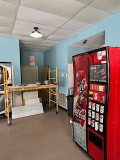 There is a coca cola vending machine in the middle of the room.