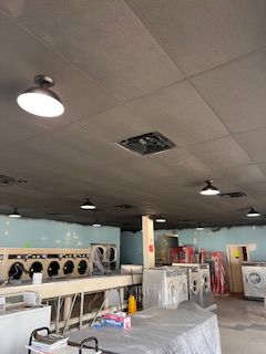 A laundromat with a lot of washers and dryers and a ceiling fan.