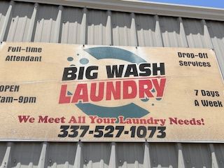 A sign for big wash laundry is on the side of a building.