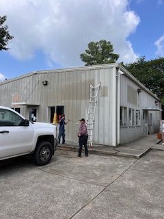 A white truck is parked in front of a building that is being painted.