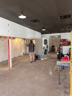 A man is standing in a room with a washer and dryer.
