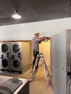 A man is standing on a ladder in a laundromat.