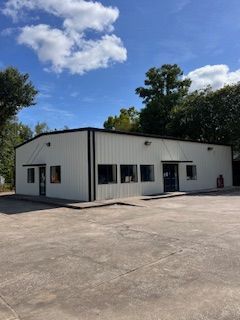 A large white building with a lot of windows is sitting on top of a concrete lot.