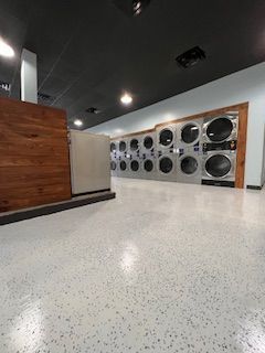 A laundromat with a lot of washing machines and dryers.