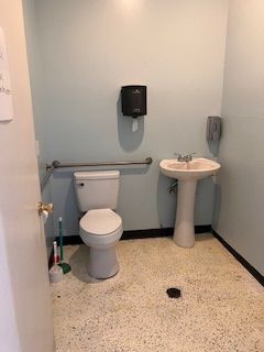 A bathroom with a toilet , sink and trash can.