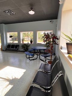 A waiting room with tables and chairs and a window.