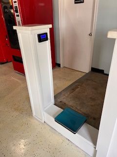 A person is standing on a scale in a room next to a vending machine.