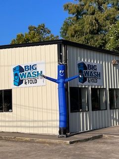 A white building with a sign that says big wash and fold