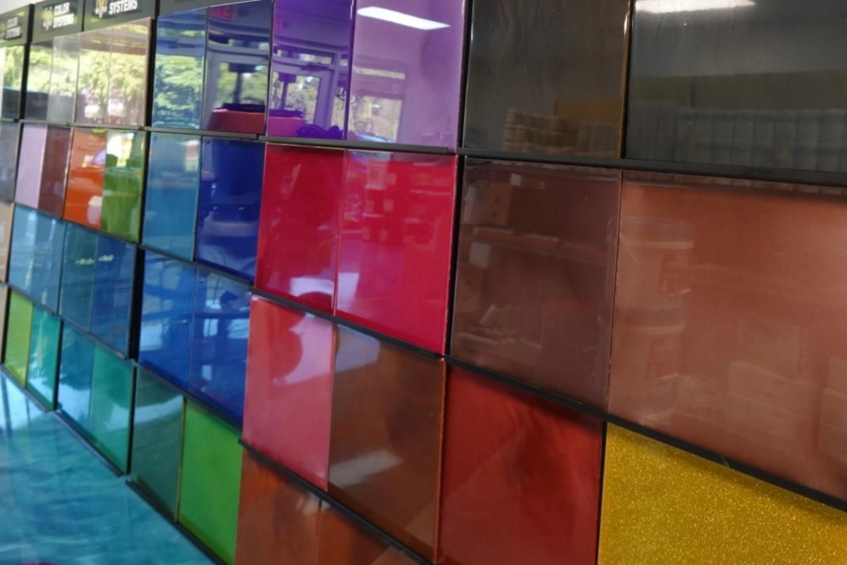 Colorful stained-glass wall with purple, red, blue, yellow, and brown panels in a corridor