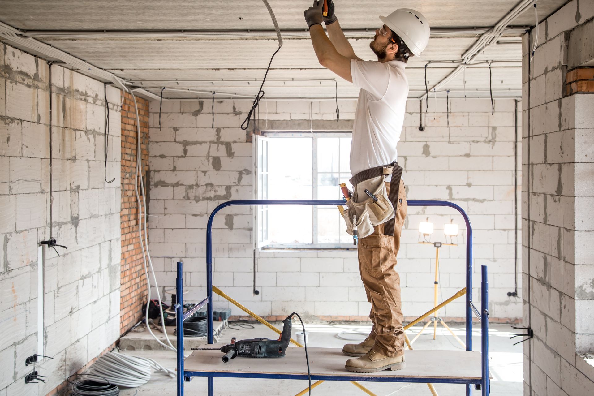 A man is standing on a scaffolding working on a ceiling.