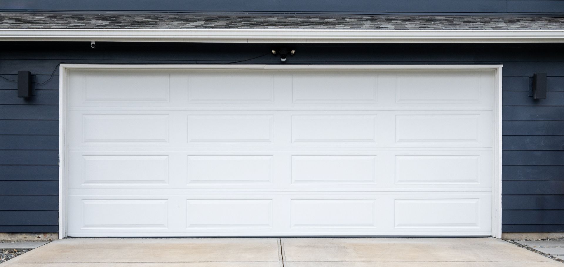 A white garage door is open on a blue house.