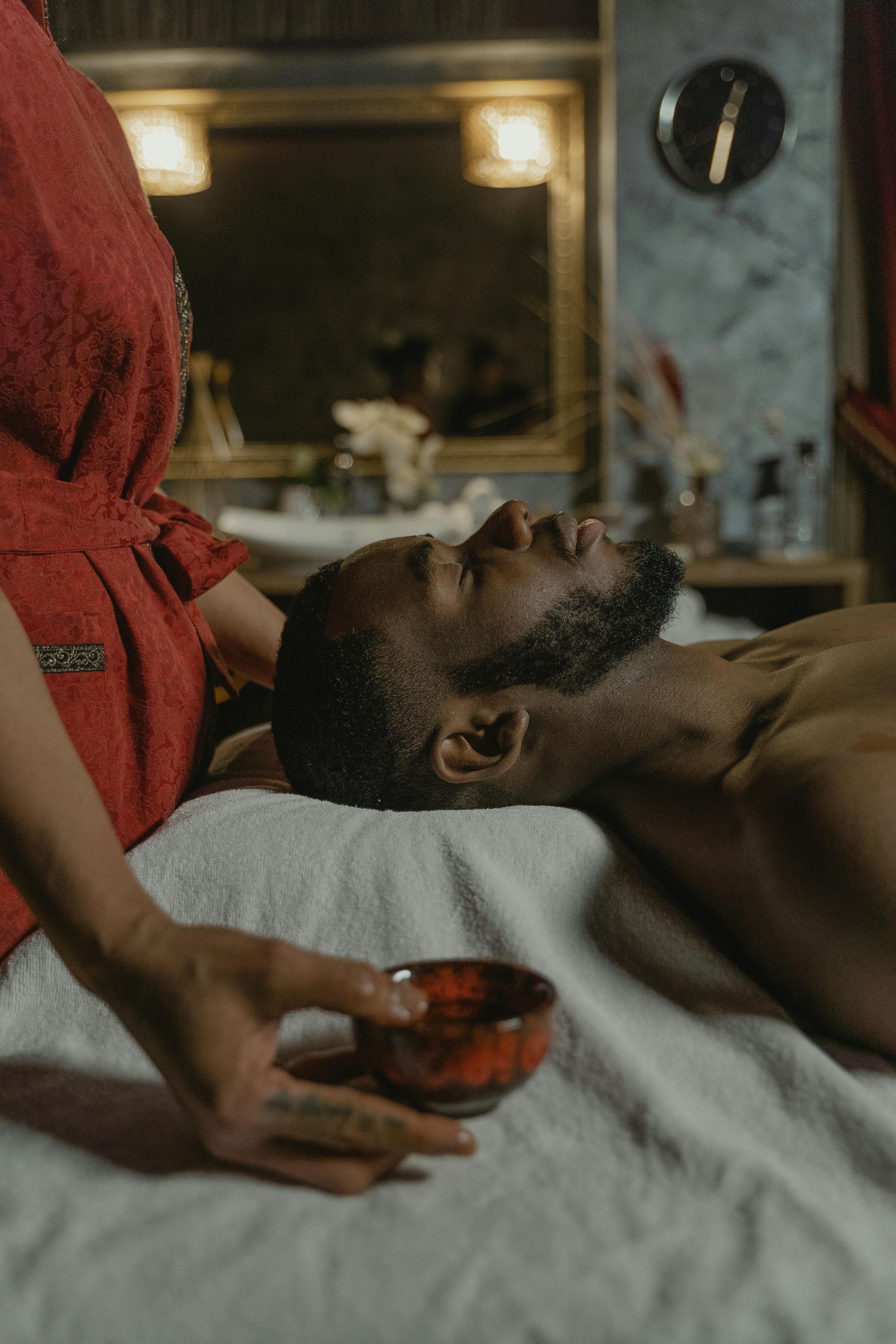 A man is laying on a bed getting a massage from a woman.