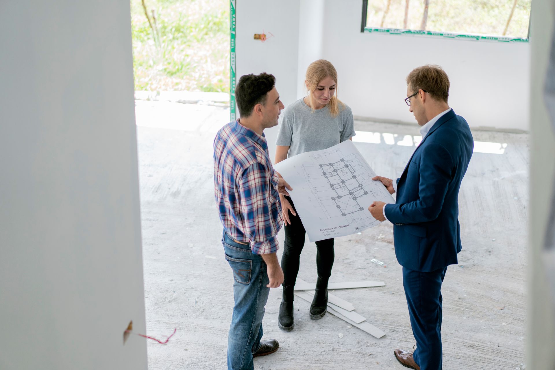 Architect holding blueprints while analyzing it with a couple at construction site.