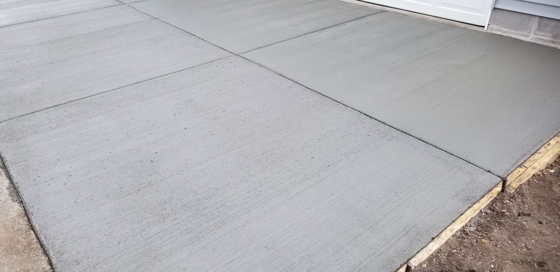 Freshly poured gray concrete patio with control joints.