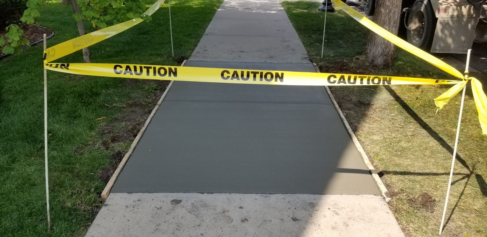 New concrete sidewalk, marked with caution tape, being constructed.