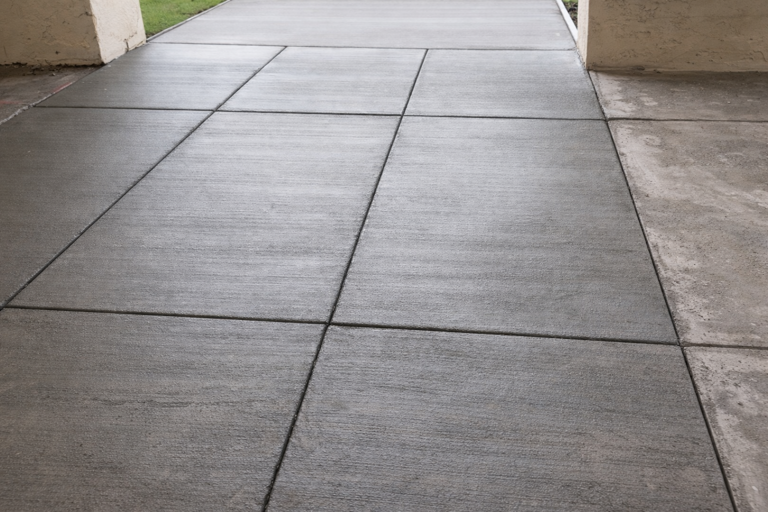 Gray concrete walkway with dark seams, near a building entrance.