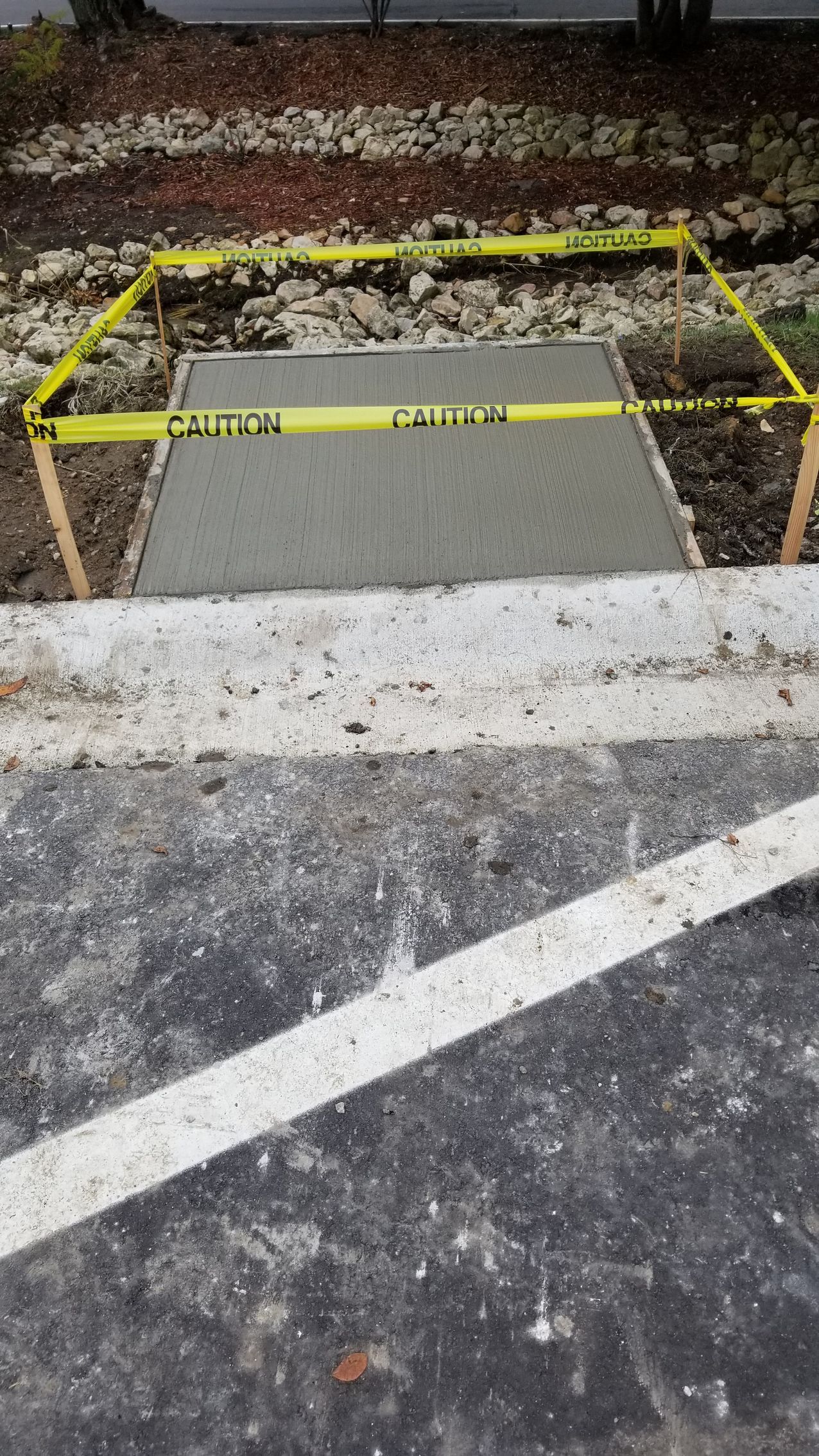 Fresh concrete sidewalk section enclosed with caution tape.