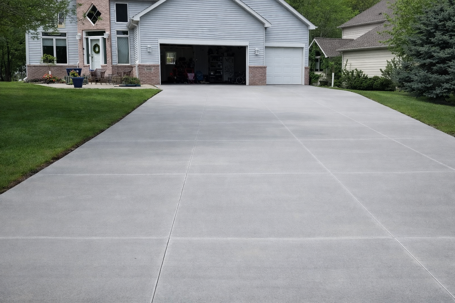 Gray concrete driveway leading to a house with a two-car garage.
