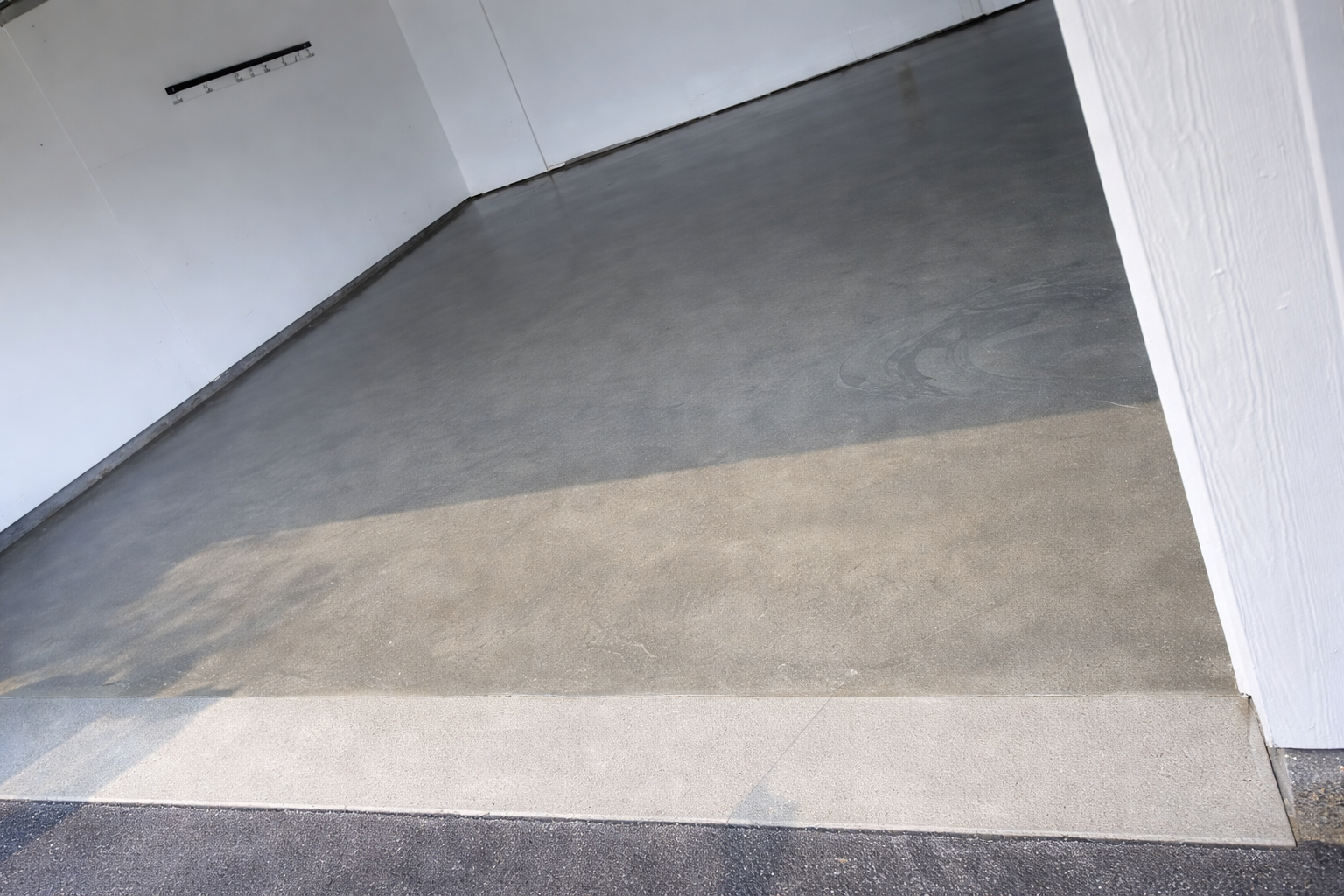 Gray concrete ramp leading from an elevated area down to a lower level, alongside white walls.