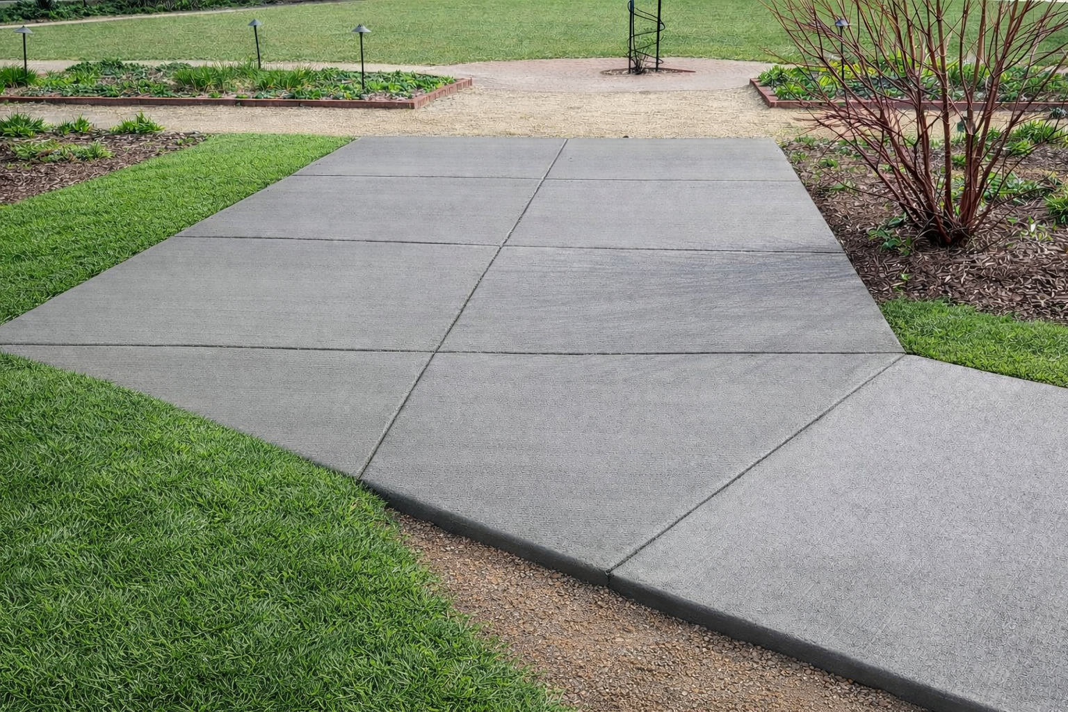 Concrete pathway with diagonal and straight lines, bordered by green grass and tan gravel.
