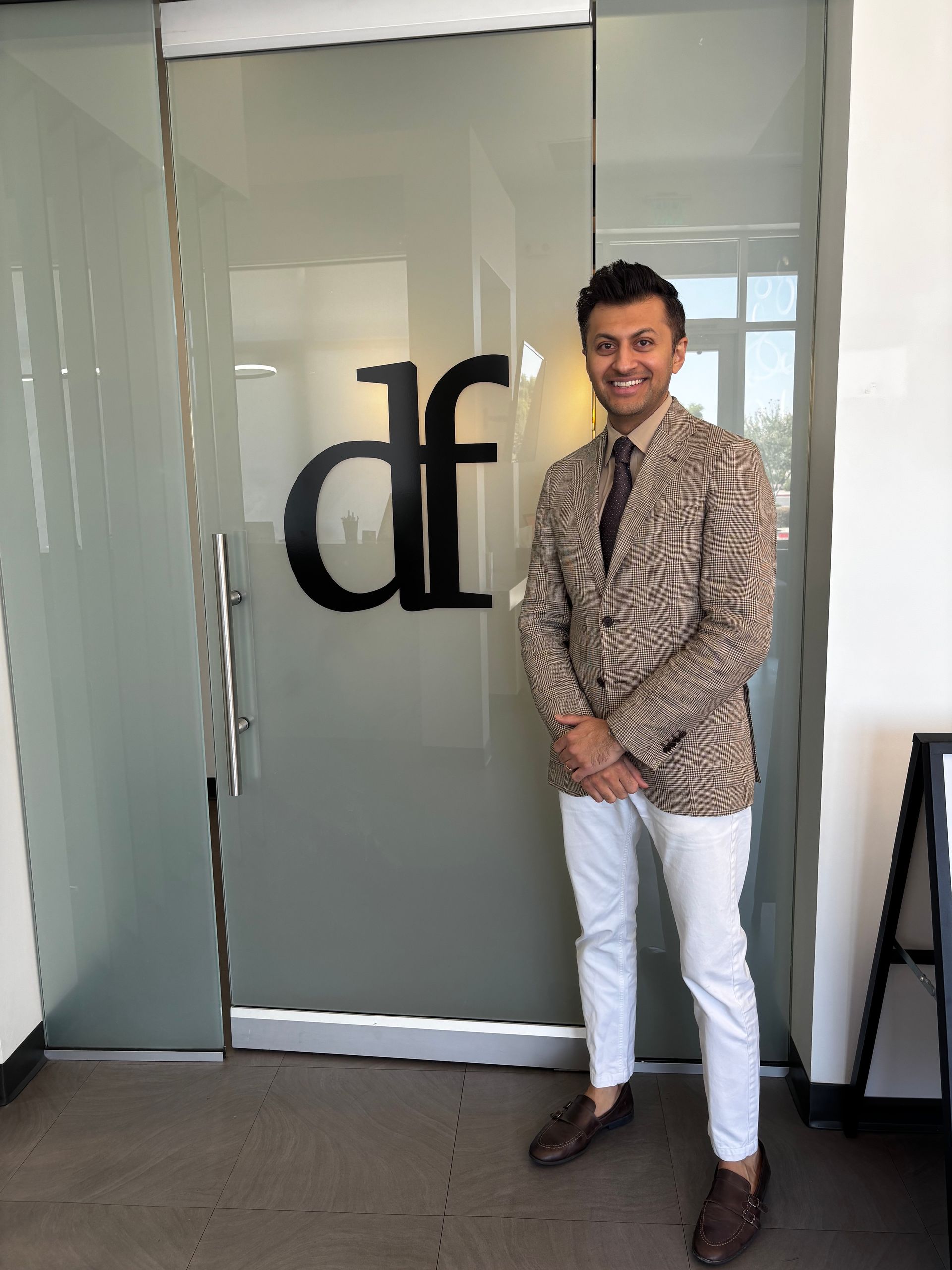 A man is standing in front of a glass door with the letter d on it