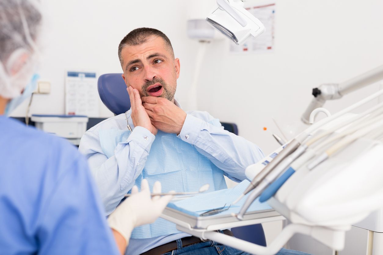 A man is sitting in a dental chair with a toothache.