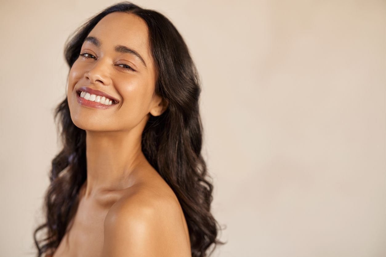 A woman with long hair is smiling and looking at the camera.