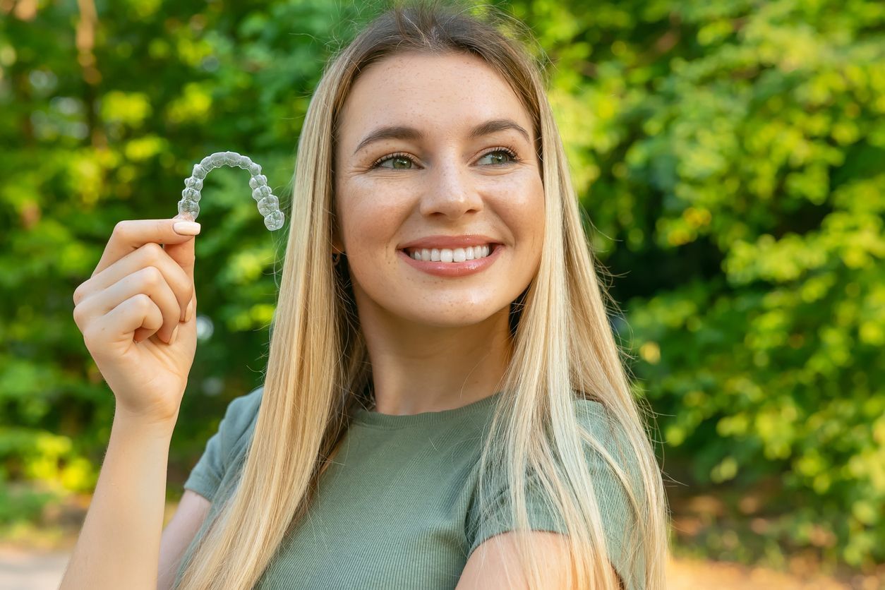 A woman is holding a clear brace in her hand.