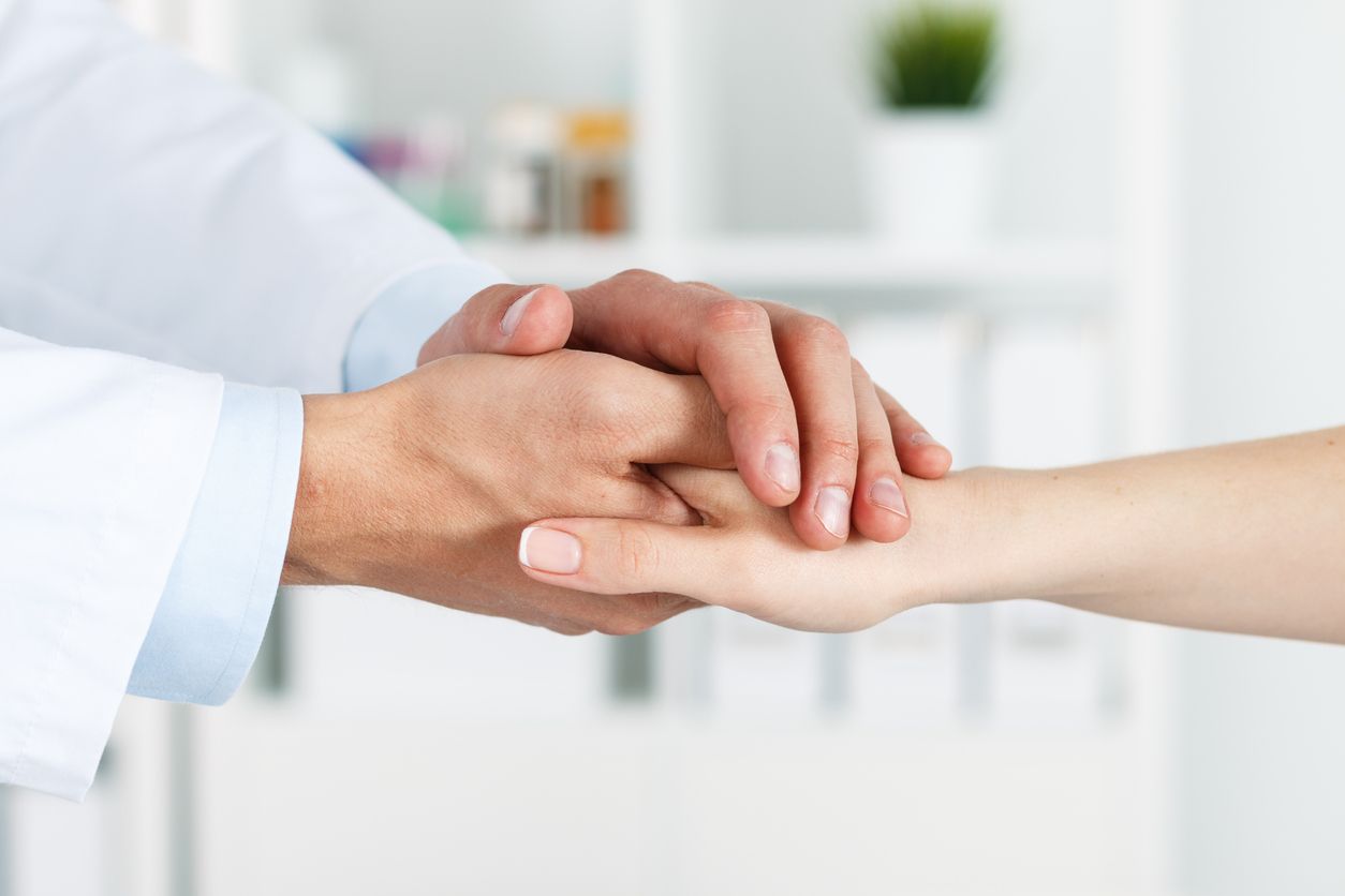 A doctor is holding a patient 's hand in a hospital.