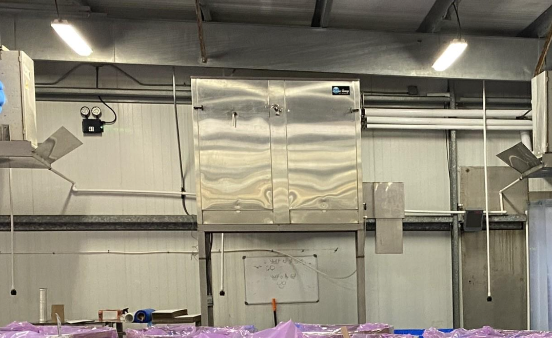 A stainless steel cabinet is hanging from the ceiling of a building.