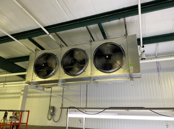 Three fans are hanging from the ceiling of a building.