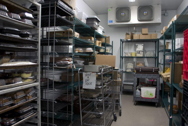A row of refrigerators in a grocery store filled with food.