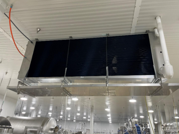 A large air conditioner is hanging from the ceiling of a factory.