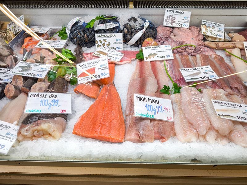 A row of refrigerators in a grocery store filled with food.