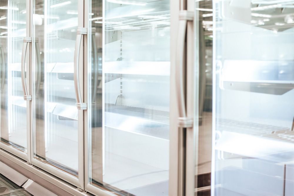 A row of empty refrigerators with glass doors in a store.