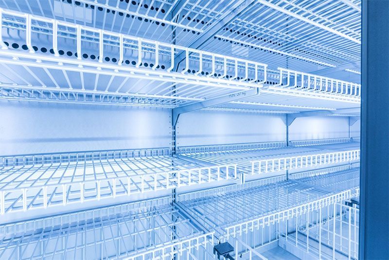 A blue and white photo of an empty refrigerator with shelves.